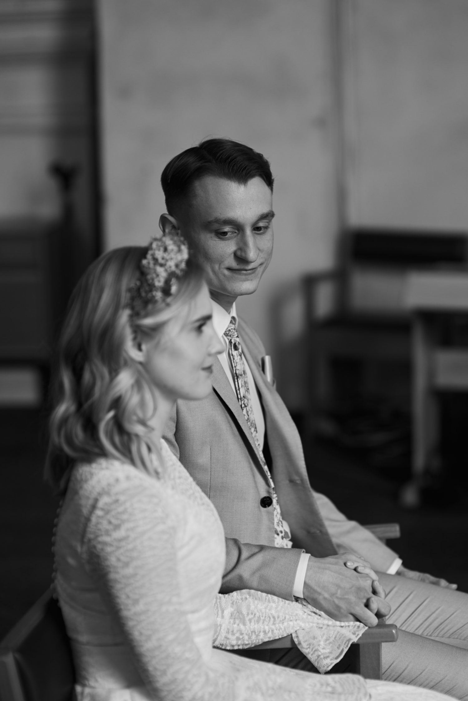 Milda ir Vilius sėdi priešais altorių bažnyčioje, ceremonija, juodai balta nuotrauka